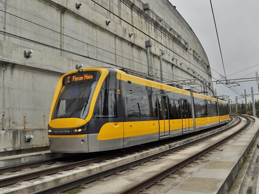 A yellow Metro do Porto tram on the surface tracks